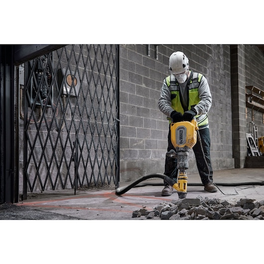 Worker using a chipping hammer D25911K to break up a concrete floor
