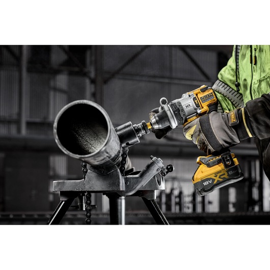 18V XR Brushless Premium Hammer Drill Driver hole cutting a large metal pipe