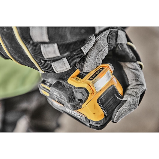 A gloved hand pushing the LED light switch on the base of the DCD800 18V XR Brushless Drill Driver 