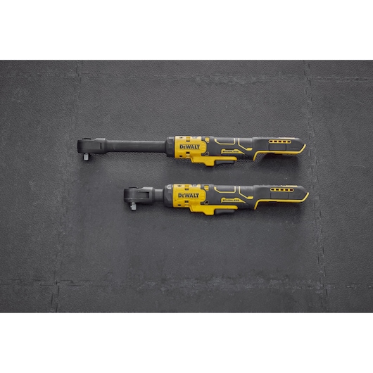Top view of two DEWALT cordless ratchet wrenches with black and yellow handles, placed side by side on a black textured surface.