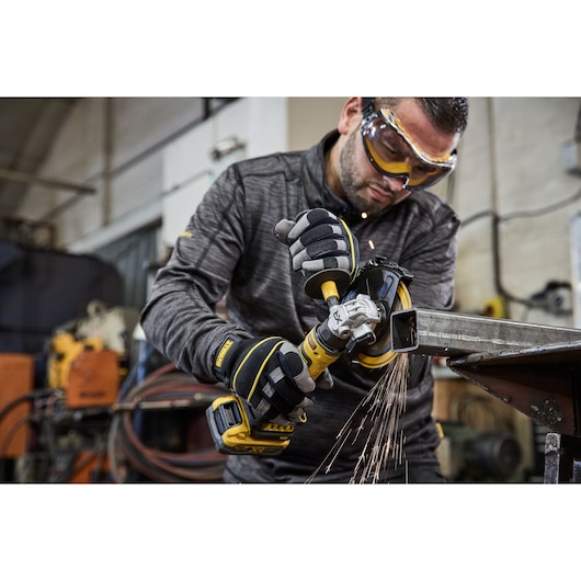 Worker uses the DEWALT 18V XR Compact 125mm Angle Grinder to cut steel square tubing