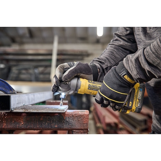 DEWALT 18V XR Compact Inline Die Grinder deburring the inside of a hole on a metal plate