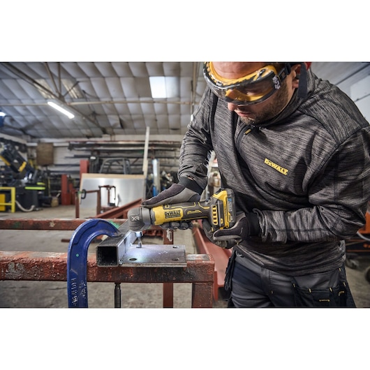 DEWALT 18V XR Compact Inline Die Grinder deburring the inside of a hole on a metal plate