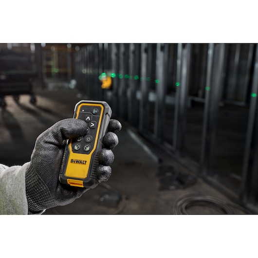 Worker holding the 18V 3X 360 Remote Control Laser remote control, adjusting laser line from meters away