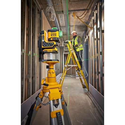 The DEWALT 18V 3X360 Remote Control Laser onsite on tripod being controlled with remote by workers.