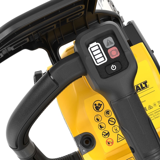 Close-up view of the handle and control panel of a DEWALT cordless chainsaw, showing battery indicator, warning symbols, and power button with detailed safety icons on the yellow body.