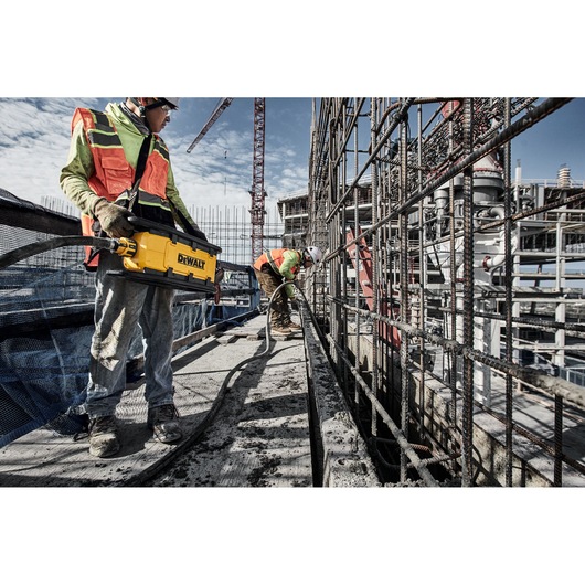 Two construction workers use Powershift Powerpack Concrete Vibrator and hose to pour concerte into a channel