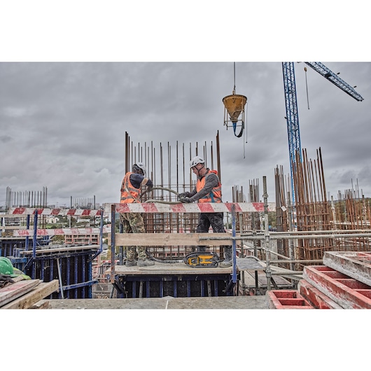 Two construction workers use Powershift Powerpack Concrete Vibrator and hose to pour concrete into a rebar column