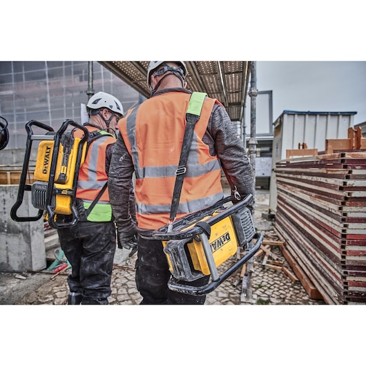 Two construction workers, each carrying a Powershift Powerpack Concrete Vibrator