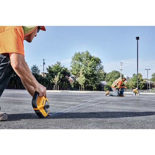 150 feet Large Capacity Chalk Reel being used by workers to mark road outdoors.