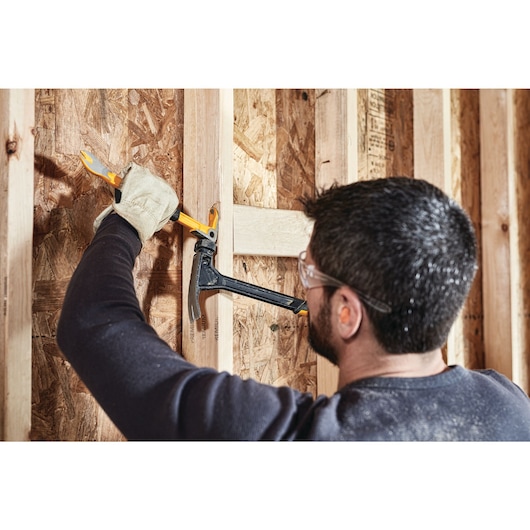 12 inch Precision Claw Bar being used with hammer by a person to pull nail from wood.