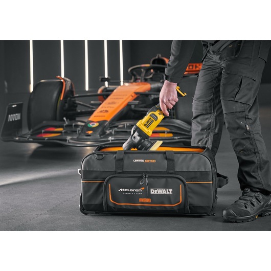 DEWALT tool being placed into a DEWALT/McLaren Duffle Bag DEWALT/McLaren Duffle Bag with wheels
